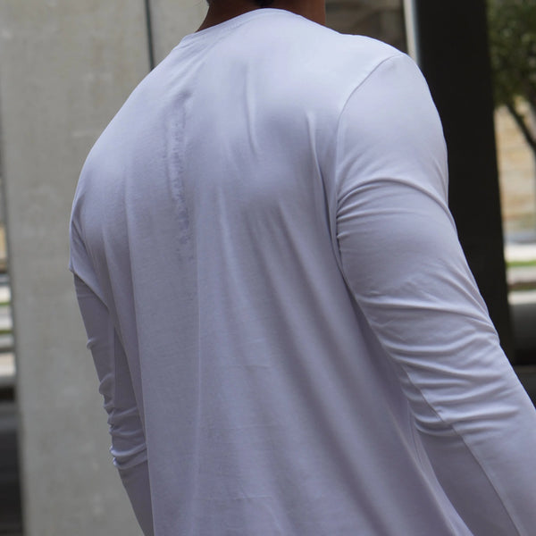 Person wearing a plain white long-sleeve shirt with a blurred background