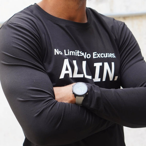 Person wearing a black long-sleeve shirt with motivational text and a watch on a light background