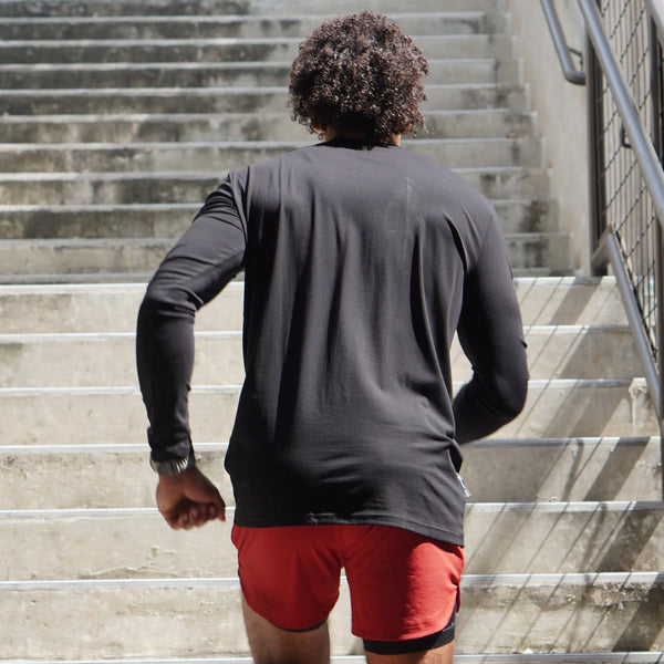 Person wearing a black long-sleeve shirt and red shorts walking up a set of stairs.