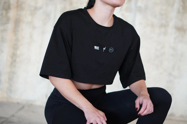 Person wearing a black t-shirt with small white graphics against a neutral background