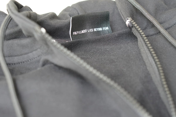 Close-up of a gray jacket with a zipper and a visible brand tag.