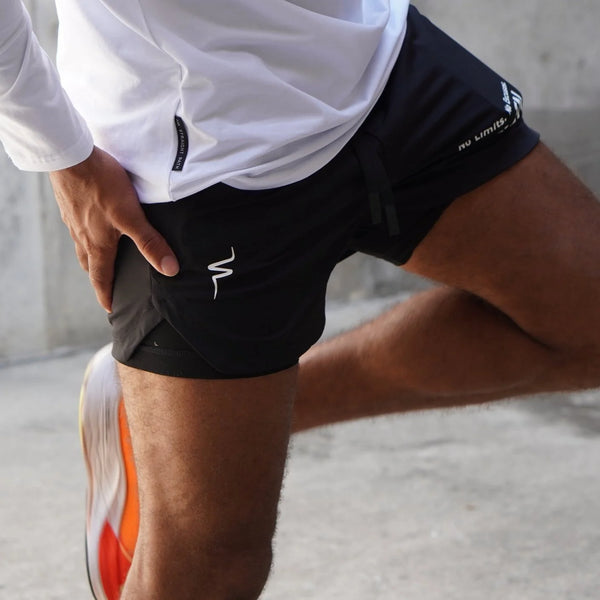 Person stretching with black athletic shorts and white shirt on a neutral background