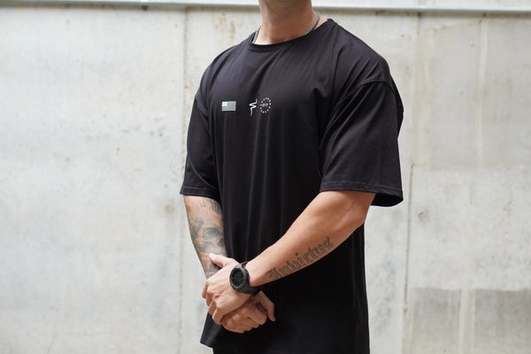 Person wearing a black t-shirt with a No Straight Path® logo against a light gray wall