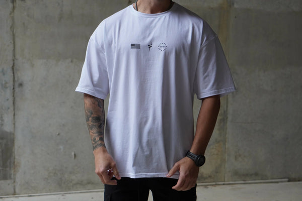 Person wearing a white t-shirt with small No Straight Path® logos against a concrete wall.