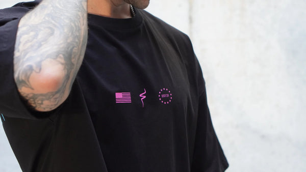 Person wearing a black t-shirt with pink No Straight Path® logos on a light gray background