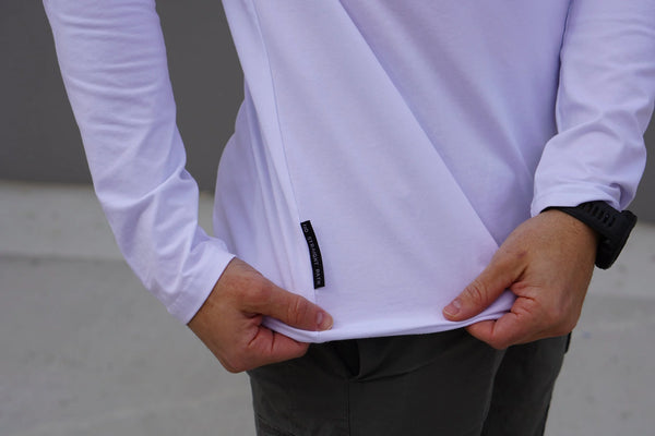 Person wearing a white long-sleeve shirt with a No Straight Path® woven tag.