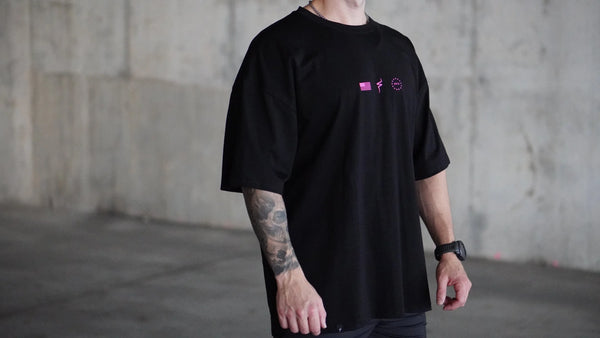 Person wearing a black t-shirt with a small No Straight Path® logo in a concrete setting