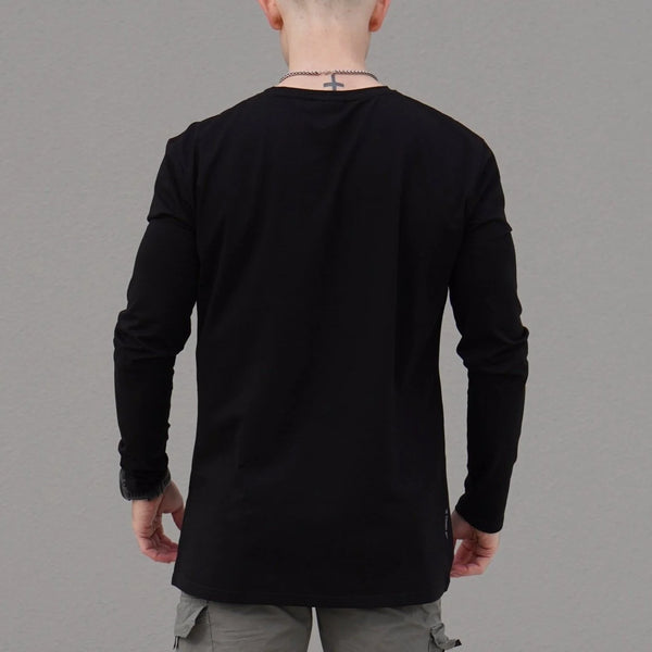 Person wearing a black long-sleeve shirt against a gray background