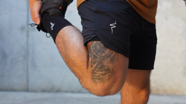 Person wearing black shorts with a No Straight Path® logo on a neutral background