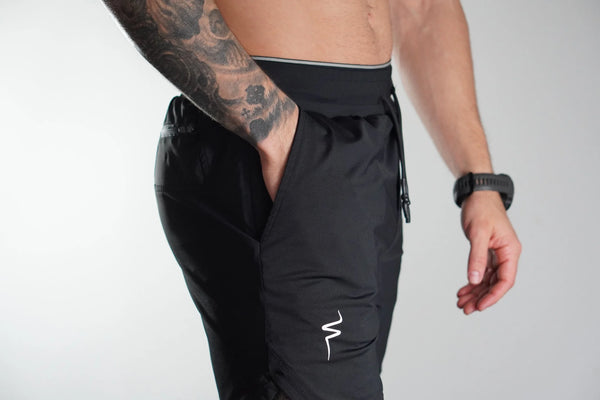Person wearing black athletic pants with a No Straight Path® logo on a white background