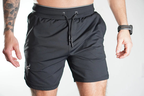 Person wearing black athletic shorts on a plain background