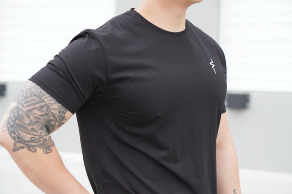 Person wearing a black t-shirt with a white No Straight Path® logo on a blurred background