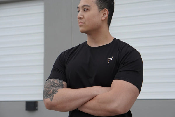 Man wearing a black t-shirt with a white No Straight Path® logo, standing against a neutral background