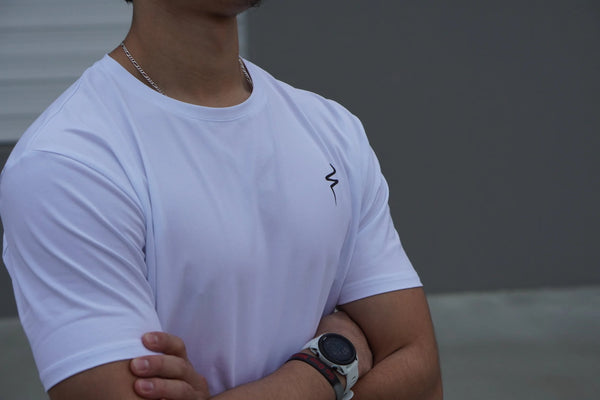 Person wearing a white t-shirt with a black No Straight Path® logo, standing against a blurred background