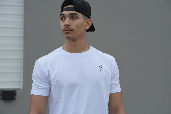 Man wearing a white t-shirt with a black No Straight Path® logo and a black cap against a gray background