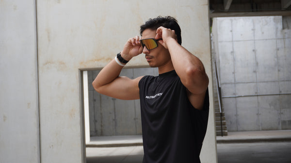 Man adjusting sunglasses in an urban setting