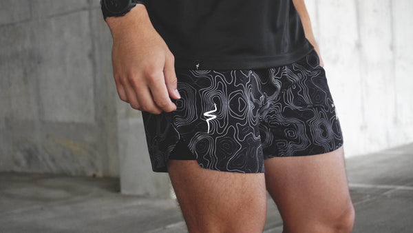 Person wearing black athletic shorts with white pattern and No Straight Path® logo.