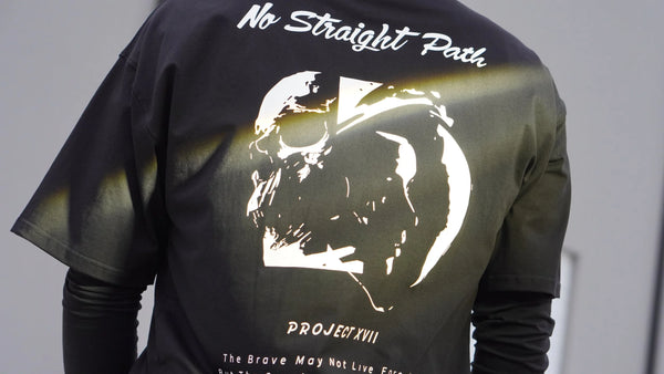 Black t-shirt with a skull design and text on the back, worn by a person.