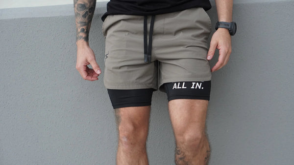 Person wearing gray shorts with 'All In.' logo against a gray background