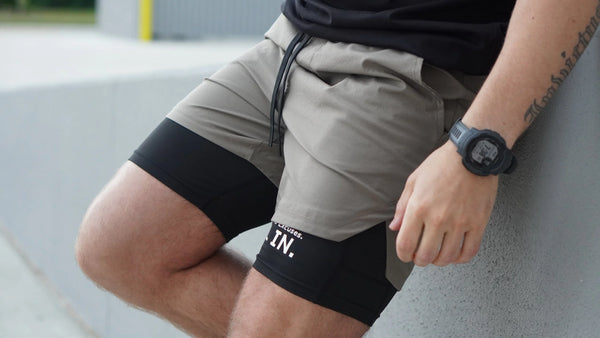 Person wearing shorts with visible No Straight Path® branding, sitting on a concrete surface.