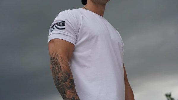 Person wearing a white t-shirt with a USA flag design on a cloudy day