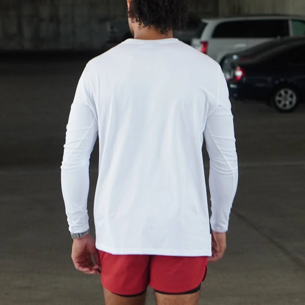 Person wearing a white long-sleeve shirt and red shorts in an outdoor setting.