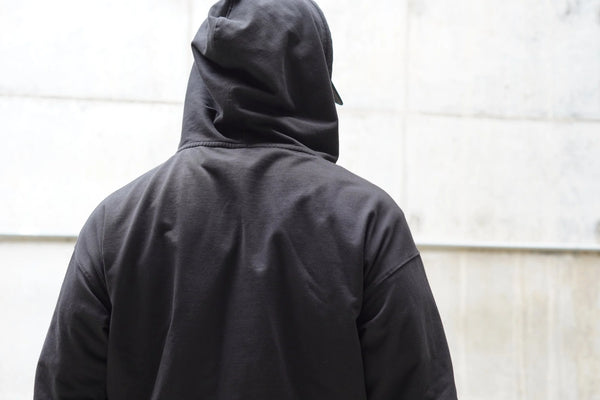 Person wearing a black hoodie with a plain background