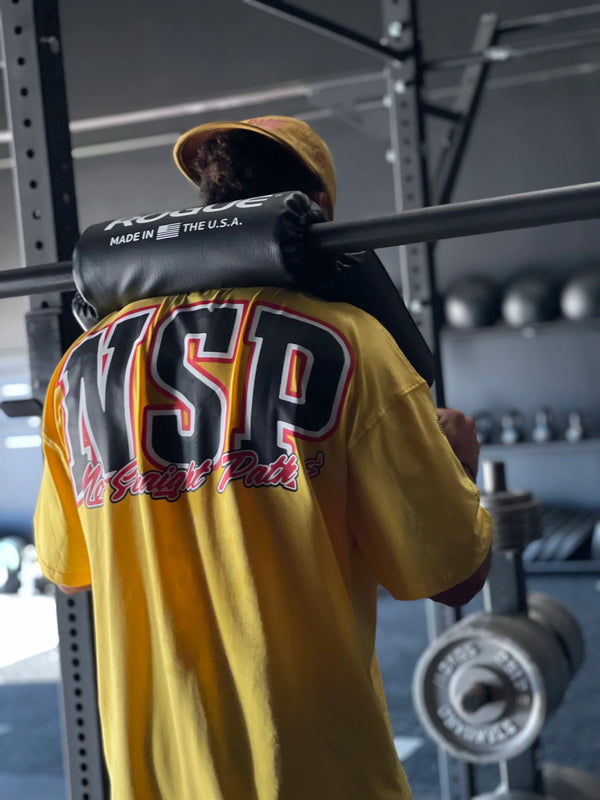 Person wearing a yellow 'NSP' shirt in a gym setting
