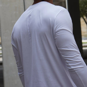 Person wearing a plain white long-sleeve shirt with a blurred background