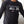 Black long-sleeve shirt with motivational text and logos on a neutral background
