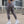 Woman wearing gray leggings and white sneakers on a rooftop with cityscape background