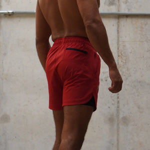 Person wearing red athletic shorts against a concrete wall.
