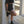 Woman wearing black shorts and shoes leaning against a concrete wall.