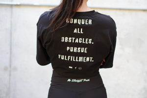 Person wearing a black shirt with motivational text reading 'Conquer all obstacles. Pursue fulfillment.' against a plain background