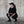 Person in black outfit squatting against a textured wall