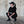 Girl in black outfit squatting against a textured wall.