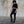 Person wearing a black outfit standing against a textured wall.