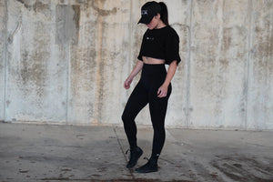 Person wearing a black outfit standing against a textured wall.