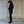 Woman wearing a black outfit standing against a textured wall.