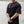 Person wearing a black t-shirt with a No Straight Path® logo against a light gray wall