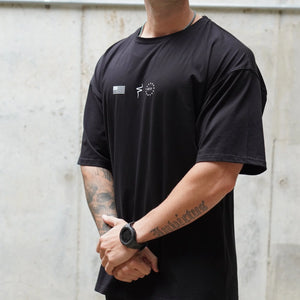Person wearing a black t-shirt with a No Straight Path® logo against a light gray wall