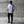 Person wearing a white t-shirt and black pants standing against a concrete wall.