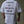 Person wearing a white t-shirt with motivational text reading 'Conquer all obstacles. Pursue fulfillment.' on the back against a concrete wall.