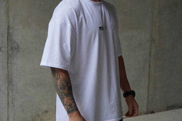 Person wearing a white t-shirt with small No Straight Path® logos against a plain background