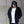 Person wearing a black hoodie and cap with a white shirt, standing against a concrete wall.