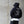Person wearing a black hoodie with text on the back against a concrete wall.