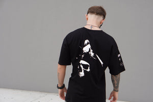 Person wearing a black t-shirt with a white skull graphic design on the back, standing against a gray background.