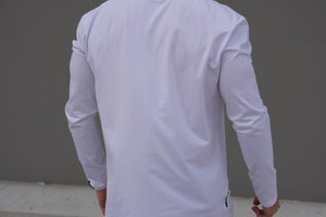 Person wearing a white long-sleeve shirt against a gray background