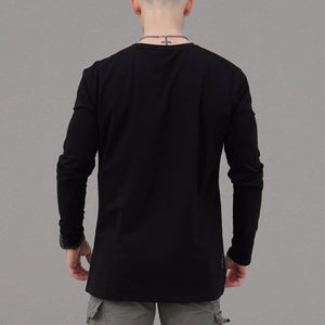 Person wearing a black long-sleeve shirt against a gray background