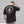 Person wearing a black t-shirt with white graphic design on the back, standing against a plain background.